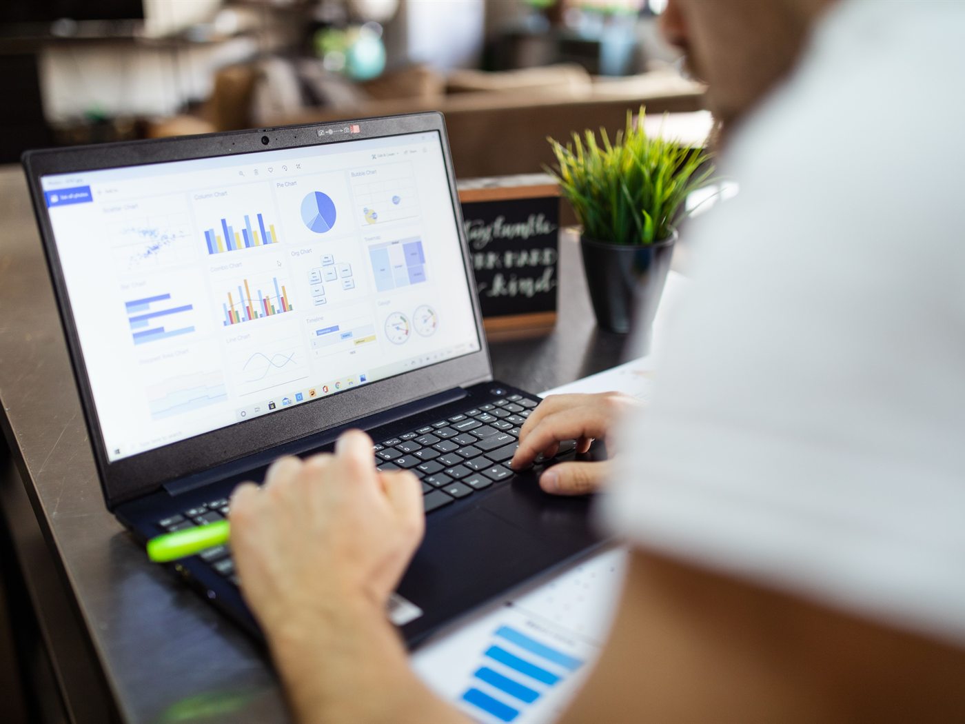 An analyst reviewing charts and reports on a laptop